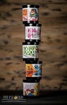 four cans stacked on top of each other in front of a wooden background with text