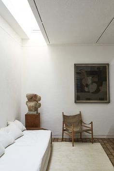 a room with a bed, chair and painting on the wall