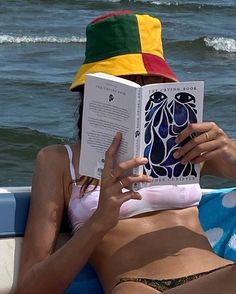 a woman laying on top of a boat reading a book