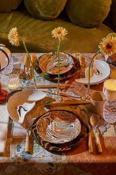 the table is set with plates, silverware and flowers