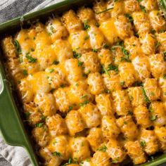 a casserole dish with cheese and green garnish on it's side