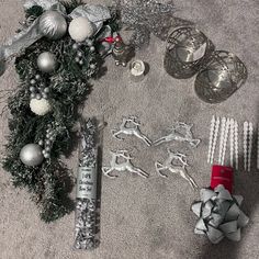 christmas decorations and ornaments are laid out on the floor next to silver candlesticks