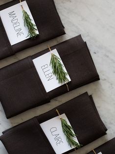 three place cards are placed on the napkins with rosemary sprigs attached to them