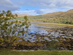 the view from a moving train looking out at water and hills in the distance with trees on either side