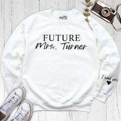 Future MRS Sweatshirt with I Said Yes on Sleeve, Custom Engagement Hoodie, Personalized Bride To Be Tshirt, Bridal Shower Tee, Married Tees  Celebrate your journey to the altar with our Future MRS Sweatshirt with I Said Yes on Sleeve, Custom Engagement Hoodie, Personalized Bride To Be Tshirt, Bridal Shower Tee, and Married Tees collection! Our custom shirts are perfect for the bride-to-be looking to showcase her excitement and style. The Future MRS Sweatshirt with I Said Yes on Sleeve is a charm White Text Print Hoodie Tops, White Text Print Hoodie, Hooded Cotton Tops With Slogan, Cotton Hooded Tops With Slogan, Bride To Be Tshirt, Mrs Hoodie, Wife Sweater, Fiance Sweatshirt, Bridal Shower Shirts