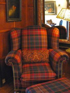 the chair is upholstered in plaid and has an intricately decorated armrest