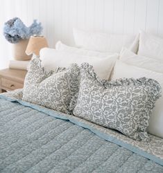 a bed with blue and white pillows on top of it