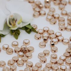 there are many small gold numbers on the table next to a flower and a white rose