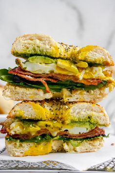 a stack of sandwiches sitting on top of a white plate next to an egg and avocado sandwich