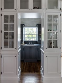 a kitchen with white cabinets and wood floors