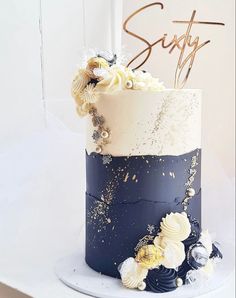 a blue and white wedding cake with flowers on the top is decorated with gold leaf