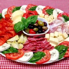 a platter filled with meat, cheese, tomatoes, olives and lettuce