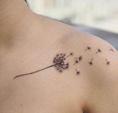 a woman's chest with a dandelion tattoo on it