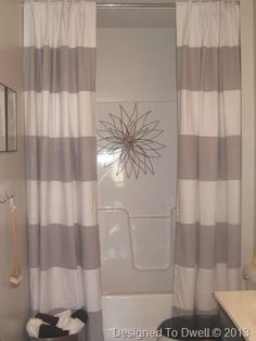 a bath room with a toilet a sink and a shower curtain on the window sill