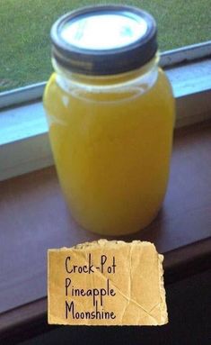 a jar of crock pot pineapple moonshine sitting on a window sill