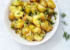 a white bowl filled with potatoes and herbs