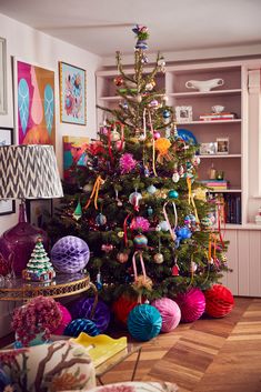 a brightly colored christmas tree in a living room with colorful ornaments on the top and bottom