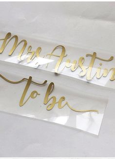 two clear acrylic stickers with gold lettering that say, mr and mrs ashton to be