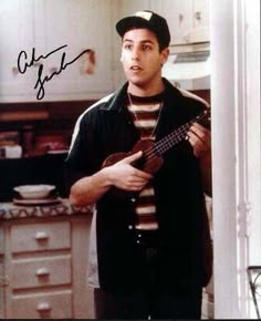 a man standing in a kitchen holding a ukulele