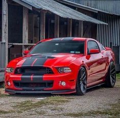 a red and black mustang parked in front of a building