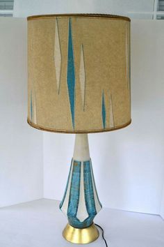 a lamp that is sitting on top of a white table with a blue and gold shade