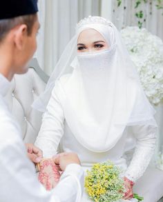 a man and woman dressed in white are getting married