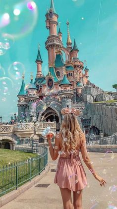 a woman in a pink dress is walking down the street with bubbles floating around her