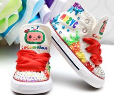 two children's shoes decorated with colorful beads and sequins are on a white surface