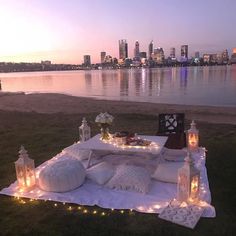 a picnic table set up on the grass with lights around it and candles in front