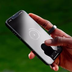 a hand holding an iphone in front of a green background with the back facing up