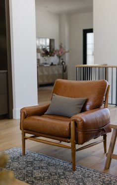 a brown leather chair sitting on top of a wooden floor next to a blue rug