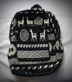 a black and white backpack with giraffes on it sitting on a bed