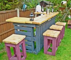 an outdoor bar made out of pallet wood with stools in the grass next to it