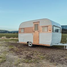 an old trailer is parked in the middle of a field