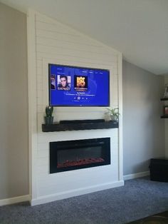 a flat screen tv mounted on the wall above a fireplace in a room with carpeted flooring