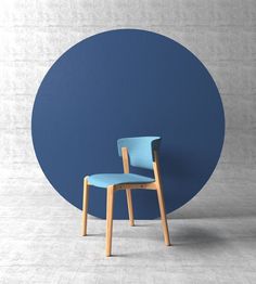 a blue chair sitting in front of a round wall with a wooden frame on it