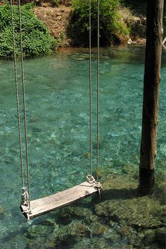 a man is swinging on a rope in the water