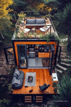 an aerial view of a tiny house in the woods with wood flooring and furniture