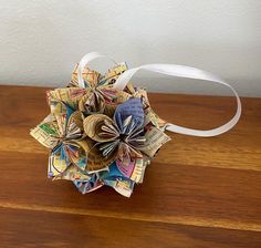 an origami flower made out of books on top of a wooden table next to a white ribbon