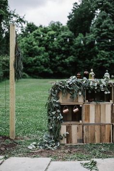 an outdoor bar made out of wooden crates with greenery and bottles on the top