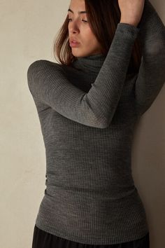 Long-sleeve high-neck tubular top made from a wool-silk blend. Merino Wool Turtleneck Top, Stretch Merino Wool Tops In Solid Colors, Stretch Merino Wool Solid Top, Fitted Elegant Merino Wool Tops, Stretch Merino Wool Solid Color Tops, Elegant Fitted Merino Wool Tops, Elegant Merino Wool Tops For Winter, Stretch Merino Wool Turtleneck Top, Fine Knit High Neck Merino Wool Top