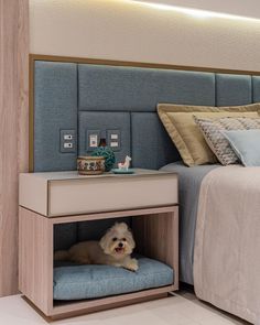 a small white dog laying on top of a bed under a night stand next to a nightstand