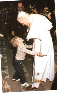 a little boy is touching the pope's hand