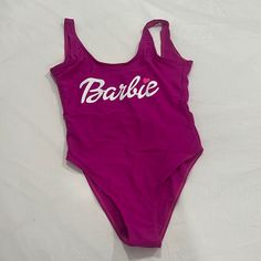 a bathing suit with the word barbie on it is laying on a white sheeted surface