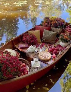 a boat filled with lots of different types of flowers and fruit on the water's surface