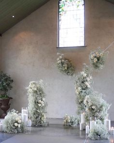 an indoor wedding setup with candles and flowers on the floor in front of a window