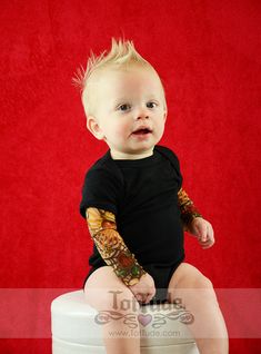 a baby sitting on top of a white stool with tattoos on it's arms