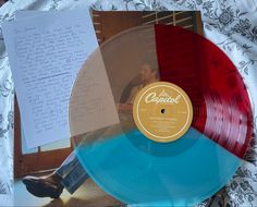 a red and blue vinyl record sitting on top of a table next to a piece of paper