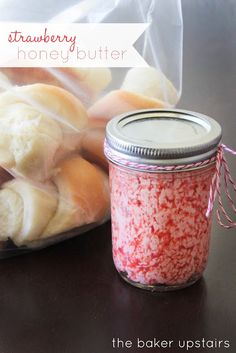 a jar filled with red and white sprinkles next to some bread rolls