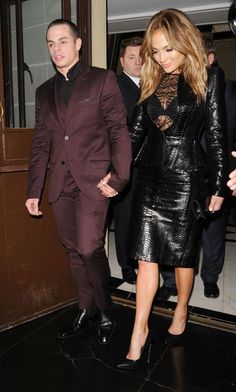 a man in a suit and tie walking next to a woman wearing a black dress